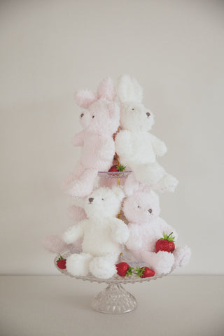Fluffy Rabbit Plush Toys in pink and white on a glass stand, surrounded by strawberries. Limited edition 10th anniversary commemorative collection.