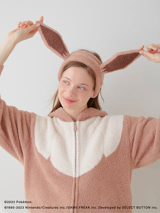 Person wearing a fluffy Pokémon Sleep Eevee hair band and matching costume, ears raised playfully. Unisex baby moco accessory.