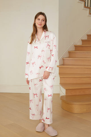 Woman wearing Ribbon Shirt & Long Pants Set with pink ribbon print, standing by stairs.