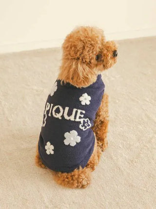Small dog wearing a navy blue flower logo jacquard pullover sweater by CAT&DOG, sitting on beige carpet, facing left.