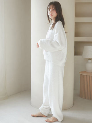 Woman wearing a cozy, white Baby Moco CAT JQD pullover sweater with relaxed sleeves and matching pants in a stylish, minimalist room.