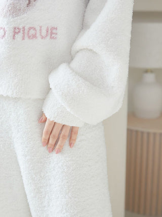 Close-up of hand touching soft fluffy Baby Moco CAT JQD Pullover Sweater, highlighting texture and relaxed sleeves with feminine design.