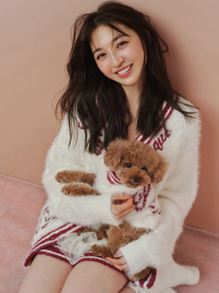 Smiling woman holding a small dog wearing a matching feather knit pullover, featuring a holiday heart pattern design, for cats and dogs.