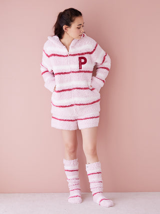 Woman wearing Gelato Border Lounge Shorts in pastel pink with cozy matching top and socks against a pastel background.