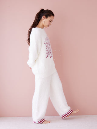 Woman wearing white Feather Pullover Sweater with festive design, showcasing cozy and elegant holiday style against pink background.
