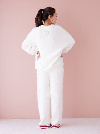 Woman wearing Feather Pullover Sweater and matching pants, showcasing its soft and cozy texture against a pink background.
