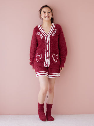 Woman wearing maroon Feather Lounge Shorts with matching sweater, showcasing festive loungewear against a soft pink backdrop.