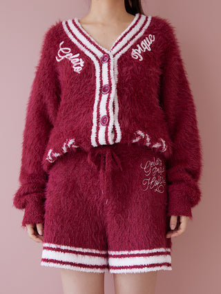 Woman wearing red feather lounge shorts and matching cardigan set, showcasing cozy festive loungewear fashion on a pink background.
