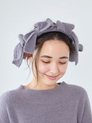 Woman wearing Gelato Pique Plush Bow Hair Ribbon in gray, displaying elegant soft bow design for stylish look.