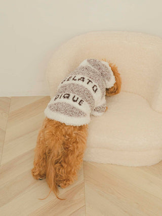 Dog wearing Gelato Melange 2 Border Hoodie, luxury pet clothing in earth tones, leaning on a soft white chair.