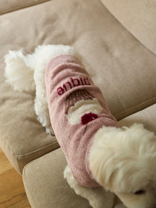 White dog wearing pink CAT&DOG cupcake sleeveless pet clothes on a beige couch.