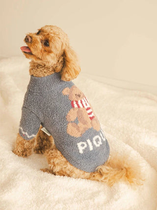 Small dog wearing CAT&DOG Nordic pet clothes with bear design, sitting on a fluffy white blanket.