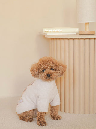 Small dog wearing CAT&DOG Heart Bear Jacquard Pet Clothes, sitting by a light wooden table in a cozy room.