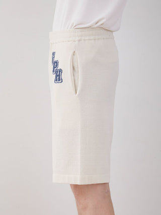 Side view of Men's Air Moco College Lounge Shorts in cream color with embroidered letters, showcasing soft and breathable fabric.