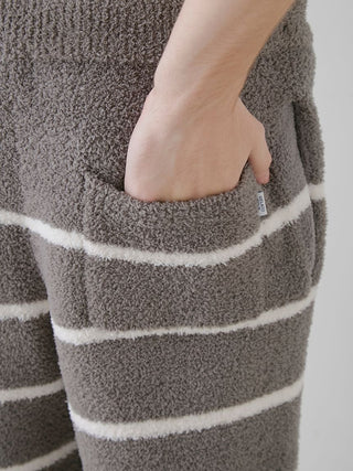 Close-up of men's powder border lounge pants with hand in pocket, featuring soft plush fabric and grey with white stripes design.