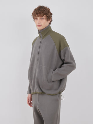 Man wearing OCEANS Plating Moco ECWCS Blouson Jacket in gray and olive green, showcasing comfortable and stylish design by Gelato Pique.