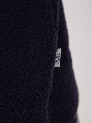 Close-up of navy Air Moco pullover sweater fabric, highlighting the plush texture and cozy design with a visible label for branding.