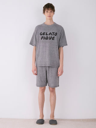 Man wearing Gelato Pique men's melange knit shirt showcasing a heathered texture with logo on chest, paired with casual shorts.