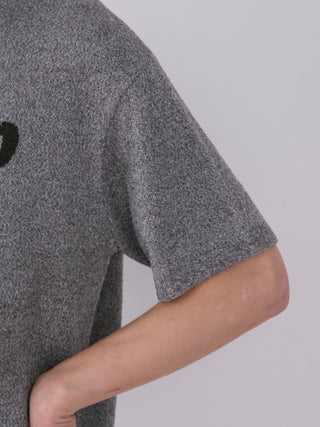 Close-up of a gray melange knit shirt with short sleeves, featuring the Gelato Pique logo in a dark tone, showcasing its textured fabric.