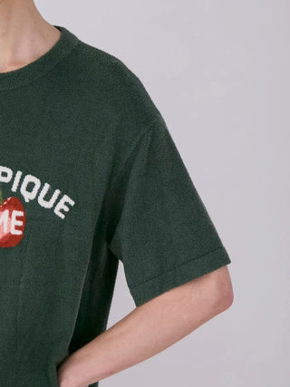 Close-up of men's fleece shirt with cherry motif and "Pique" text in green fabric.