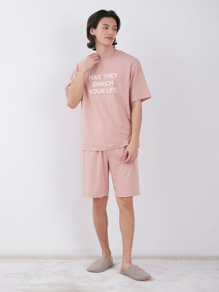 Man wearing Sarafree Logo Men's Loungewear Set in pink, featuring a comfortable t-shirt and shorts, standing in a relaxed pose.