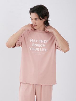 Man wearing Sarafree Logo Men's Loungewear Set in pink with "May They Enrich Your Life" text on the shirt, showcasing comfort and style.
