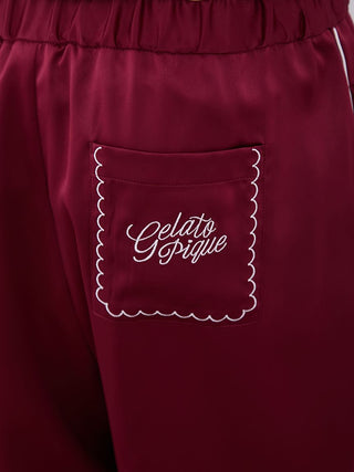 Burgundy satin pajama pants with white piping and "Gelato Pique" embroidery on pocket