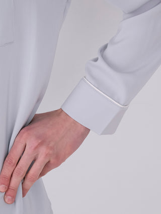 Close-up of a hand touching a men's satin shirt sleeve, showcasing the smooth, silky fabric and elegant design details.