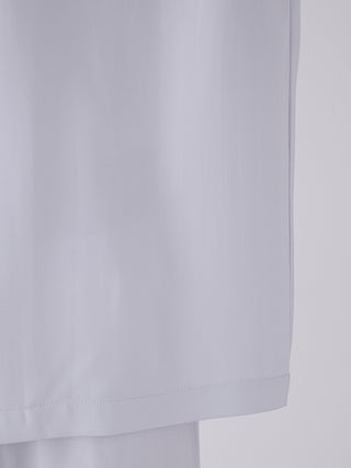 Close-up of a men's satin shirt showing smooth fabric texture, tailored hem, and premium craftsmanship in soft grey color for luxurious loungewear.
