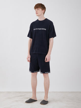 Model wearing men's smoothie light comfy lounge shorts and matching t-shirt, showcasing a casual loungewear style with slippers.
