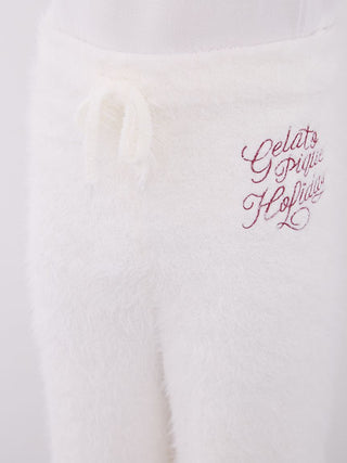 Close-up of white feather pajama pants with festive embroidery, highlighting soft fabric and cozy design.