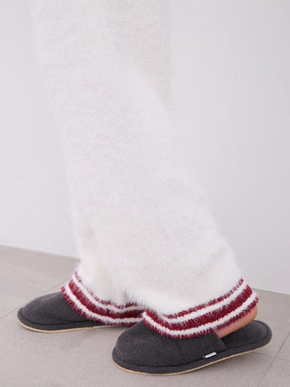 Close-up of men's feather pajama pants in white with red striped slippers, showcasing soft fabric texture and cozy comfort.