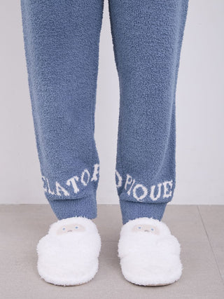 Close-up of Gelato Pique "Powder Logo" pajama pants featuring logo detail at the cuffs, with plush white slippers on a grey floor.