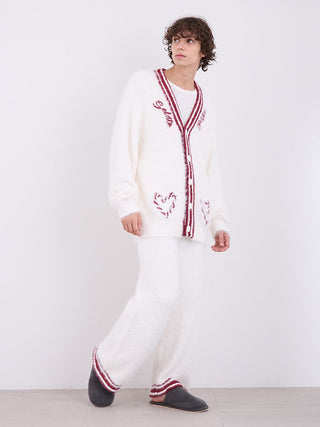 Man wearing cozy white feather-textured button-up cardigan with red detailing, styled for festive elegance.