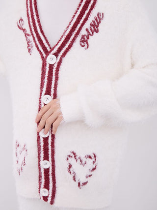 Close-up of a white mens feather button up cardigan with red stripes and heart details, showcasing button closure and festive design.