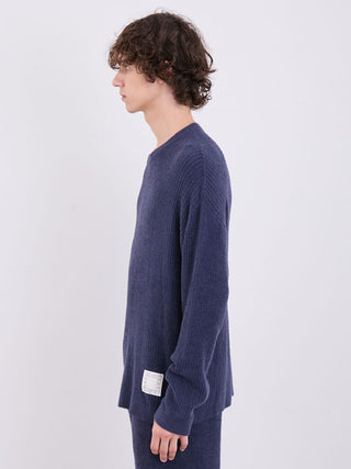 Side view of a man wearing a navy blue ribbed long sleeve sweater, perfect for a cozy and fashionable look.
