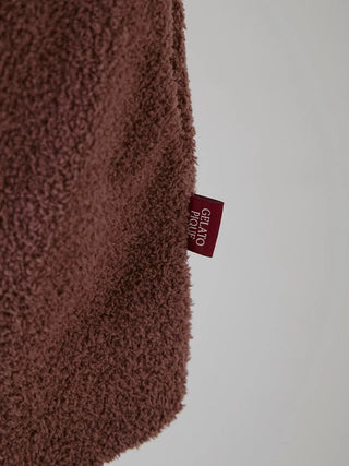 Close-up of Gelato Pique label on brown plush cardigan fabric.