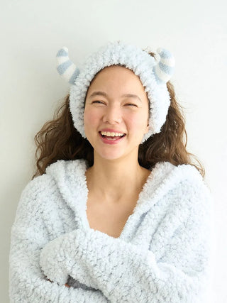 Smiling person wearing Pique Monster headband with plush horns, perfect for Halloween. Enhance your costume with whimsical style.