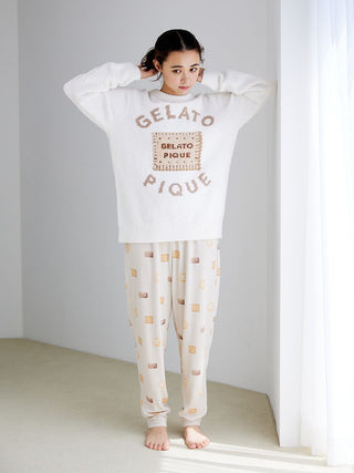 Woman in biscuit pattern waffle pajama pants by Gelato Pique, standing in a well-lit room, showcasing cozy and playful nightwear.