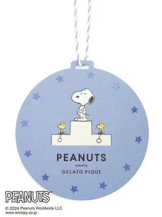 Snoopy standing on podium tag from PEANUTS meets Gelato Pique collection, surrounded by stars on a blue background.