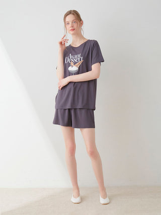 Woman wearing a COOL Rayon Dessert Logo Relaxed Fit T-shirt in dark color, featuring an "Avant Dessert" print, styled casually for comfort.