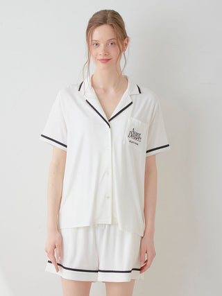 Woman wearing COOL Rayon Logo Button-Up Sleep Shirt in white with black trim, offering a chic, comfortable loungewear look.
