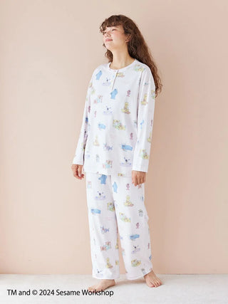 Woman wearing Sesame Street all-over print pullover and pants set in soft rayon-blend fabric, featuring happy, colorful patterns.