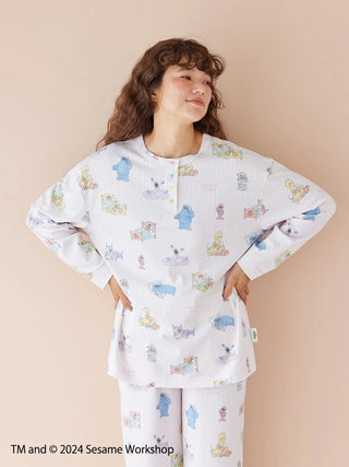 Woman wearing Sesame Street all-over print pullover in pastels, featuring a cozy Henley-neck design.