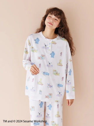 Woman wearing a cozy SESAME STREET all-over print pullover with colorful characters.