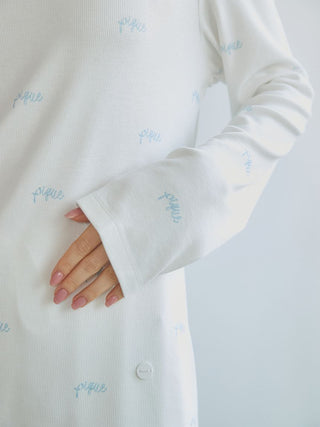 Close-up of white long sleeve t-shirt with blue bow motif pattern, showcasing soft fabric and elegant design.