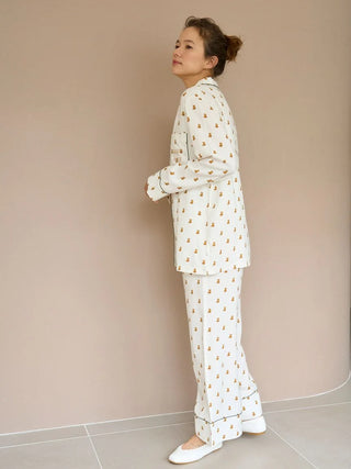 Woman wearing white, patterned Variation Pajama Pants and top, standing against a neutral background.