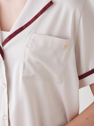 Close-up of a lined satin sleep shirt with a collar, showcasing luxurious sheeny fabric and chic burgundy line design on white.