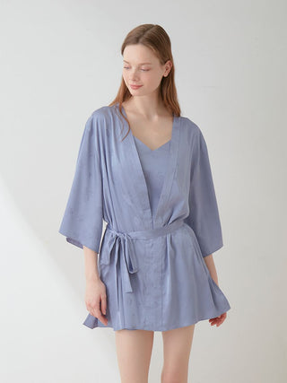 Woman wearing a light blue satin tie nightgown robe with floral pattern and long sleeves, showcasing elegant loungewear fashion.
