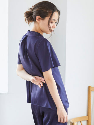 Woman wearing blue satin sleep shirt, side view showcasing elegant button-up design.